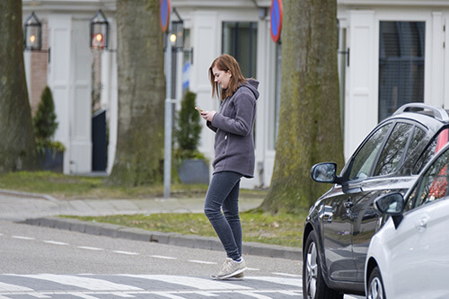 Situation on the street: girl crosses road without noticing the car